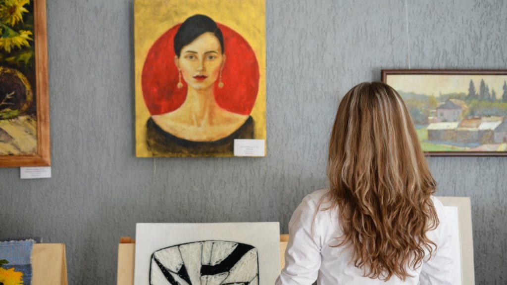 woman looking at paintings displayed on the wall